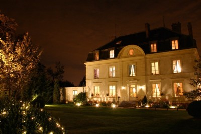 Salle de réception élégante avec vue sur un jardin verdoyant, une arche fleurie et des tables dressées.