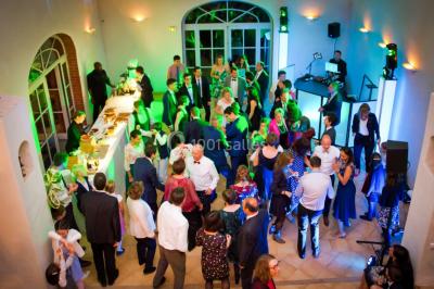 Allée bordée de palmiers éclairés, menant à une fontaine illuminée dans un jardin au crépuscule.