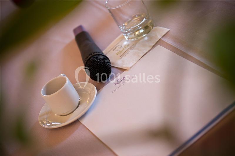 Microphone, tasse à café, verre d'eau et bloc-notes sur une table avec une serviette en papier.