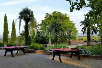 Allée bordée de palmiers éclairés, menant à une fontaine illuminée dans un jardin au crépuscule.