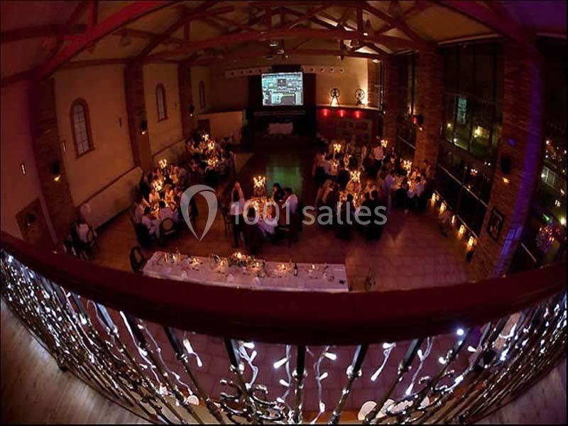 Salle de réception décorée avec des tables éclairées par des bougies, vue depuis une mezzanine ornée de guirlandes…