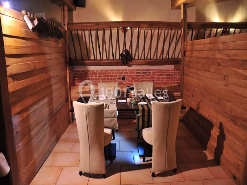 Salle de restaurant avec deux tables dressées, entourées de cloisons en bois et décorations rustiques.