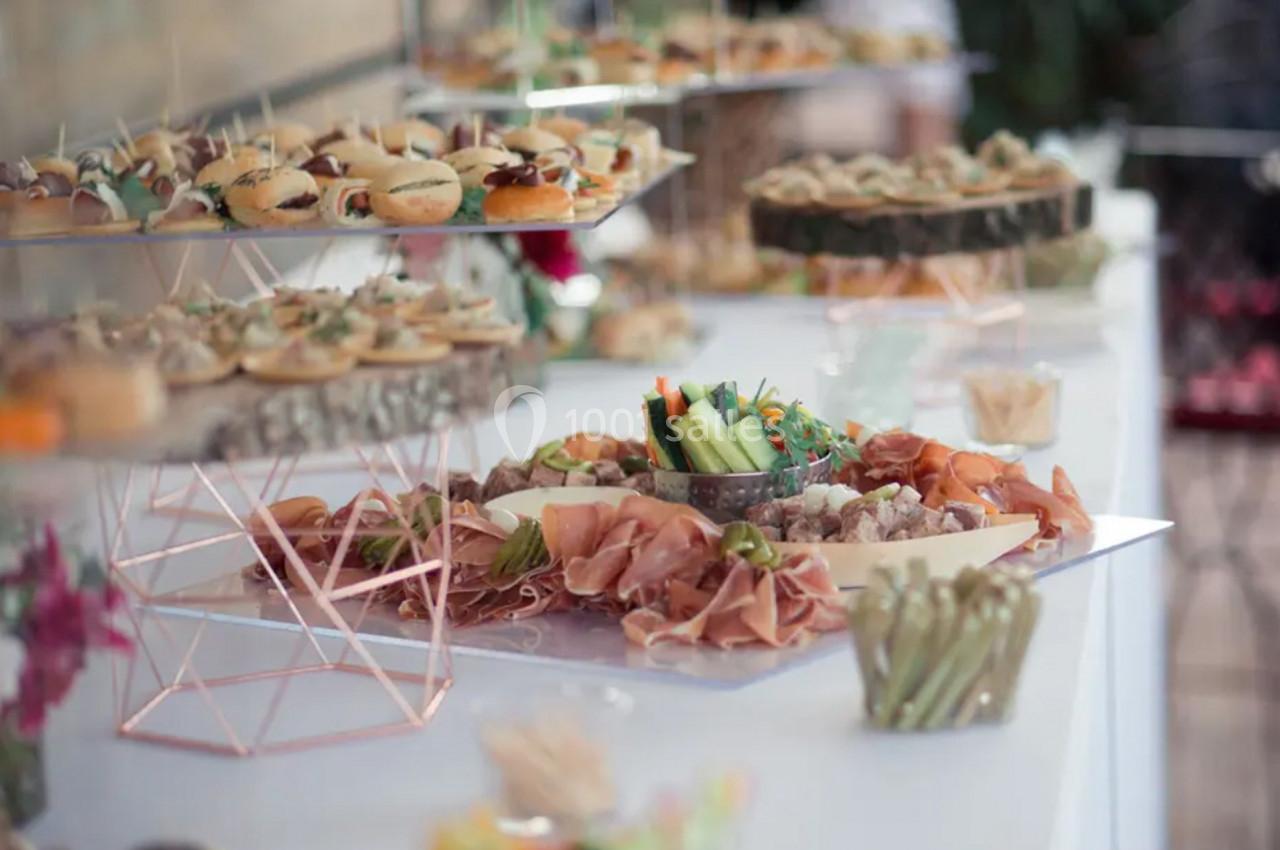Buffet avec plateaux de charcuterie, légumes frais, mini-sandwichs et amuse-bouches sur une table décorée.