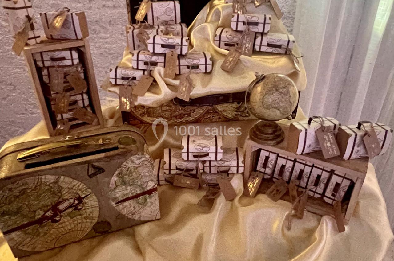 Présentoir décoratif avec des boîtes cadeaux ornées de rubans, disposées sur un tissu doré dans un cadre intérieur.