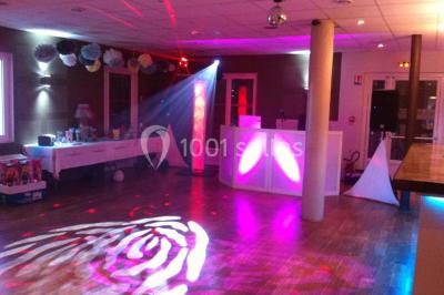 Château gonflable blanc installé sur une surface gravillonnée, entouré de végétation et de mobilier de jardin.