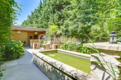 Château gonflable blanc installé sur une surface gravillonnée, entouré de végétation et de mobilier de jardin.