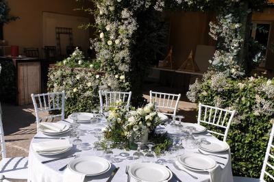 Château gonflable blanc installé sur une surface gravillonnée, entouré de végétation et de mobilier de jardin.