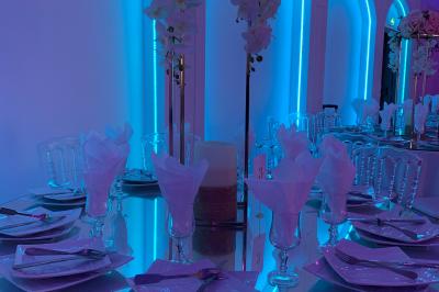 Centre de table décoratif avec bougie, fleurs blanches et roses, entouré de cadeaux sur une table de réception élégante.