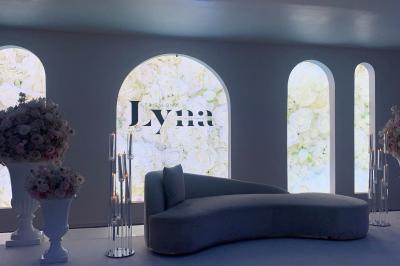 Centre de table décoratif avec bougie, fleurs blanches et roses, entouré de cadeaux sur une table de réception élégante.