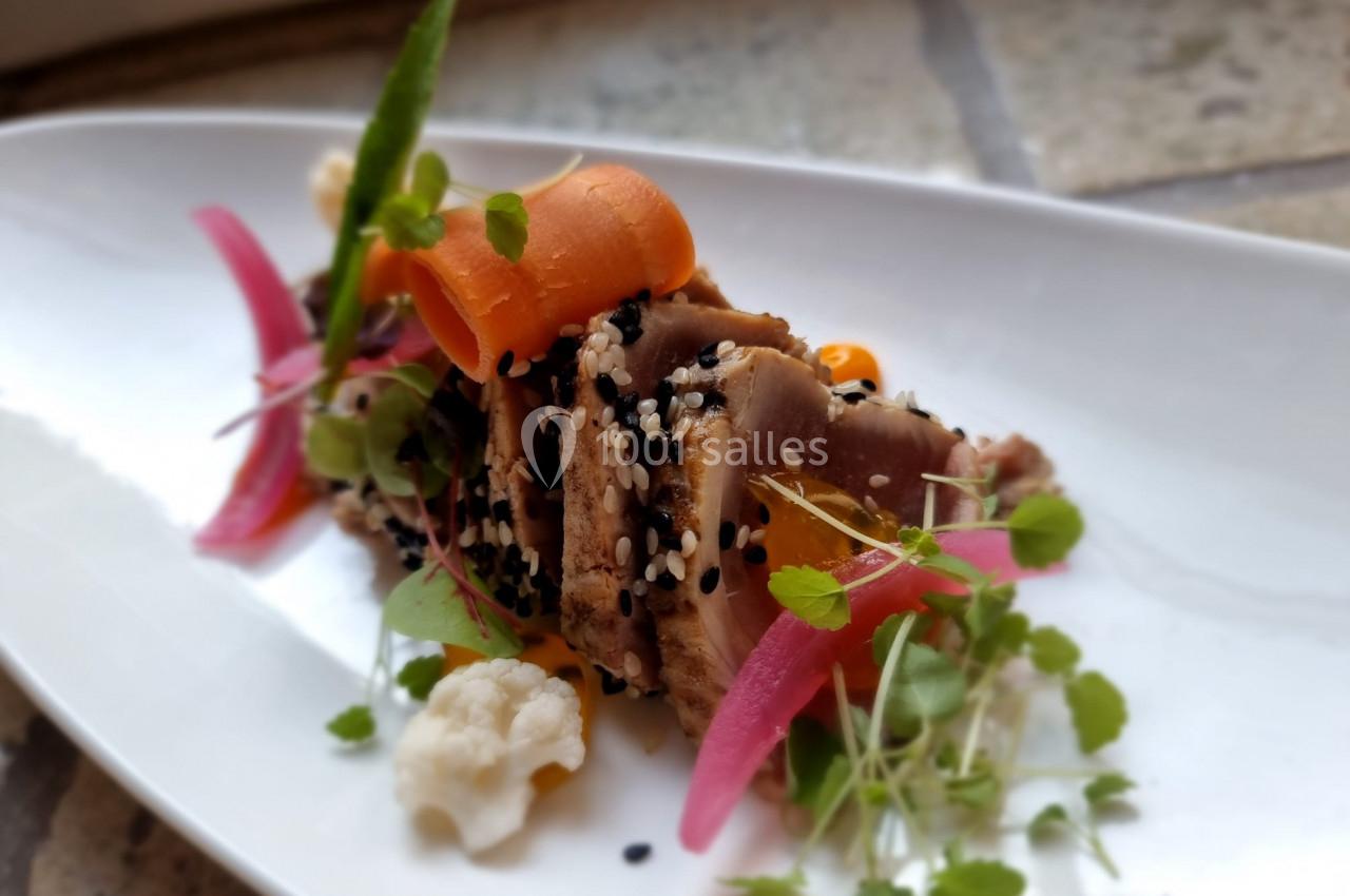 Assiette de thon mi-cuit en croûte de sésame, accompagnée de légumes colorés et de jeunes pousses.