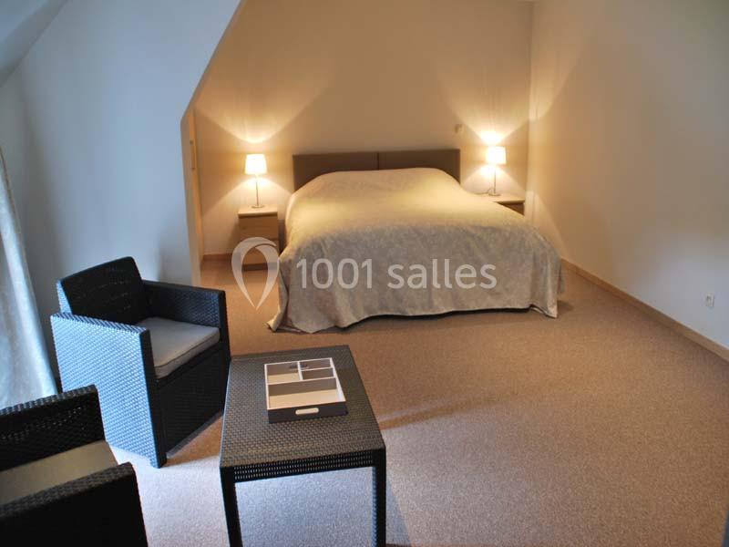 Location salle Ciney (Province de Namur) - Le Domaine d'Achêne #10 Chambre avec lit double, deux lampes de chevet, fauteuils en osier et table basse dans un intérieur sobre.