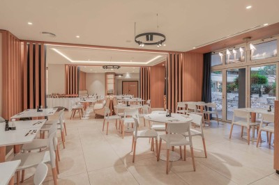 Miniature Location salle Saint-Laurent-du-Var (Alpes-Maritimes) - Playamesa #27 Chambre d'hôtel lumineuse avec lit double, bureau, fauteuil, grandes fenêtres et vue sur un balcon.