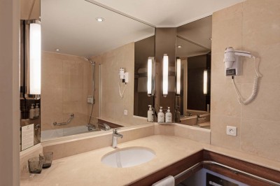 Miniature Location salle Saint-Laurent-du-Var (Alpes-Maritimes) - Playamesa #32 Chambre d'hôtel lumineuse avec lit double, bureau, fauteuil, grandes fenêtres et vue sur un balcon.