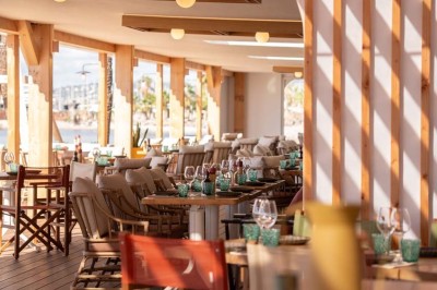 Miniature Location salle Saint-Laurent-du-Var (Alpes-Maritimes) - Playamesa #4 Chambre d'hôtel lumineuse avec lit double, bureau, fauteuil, grandes fenêtres et vue sur un balcon.