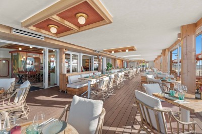 Miniature Location salle Saint-Laurent-du-Var (Alpes-Maritimes) - Playamesa #13 Balcon avec table et chaises blanches, vue sur des palmiers, la mer et un ciel bleu, sous un toit en panneaux blancs.