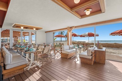 Miniature Location salle Saint-Laurent-du-Var (Alpes-Maritimes) - Playamesa #14 Balcon avec table et chaises blanches, vue sur des palmiers, la mer et un ciel bleu, sous un toit en panneaux blancs.