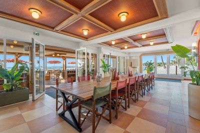 Miniature Location salle Saint-Laurent-du-Var (Alpes-Maritimes) - Playamesa #5 Balcon avec table et chaises blanches, vue sur des palmiers, la mer et un ciel bleu, sous un toit en panneaux blancs.