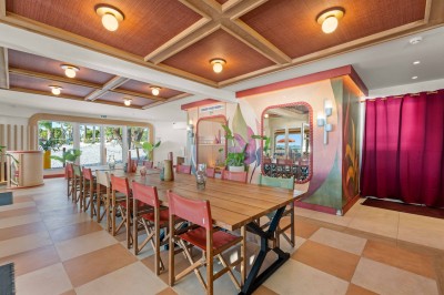 Miniature Location salle Saint-Laurent-du-Var (Alpes-Maritimes) - Playamesa #8 Balcon avec table et chaises blanches, vue sur des palmiers, la mer et un ciel bleu, sous un toit en panneaux blancs.