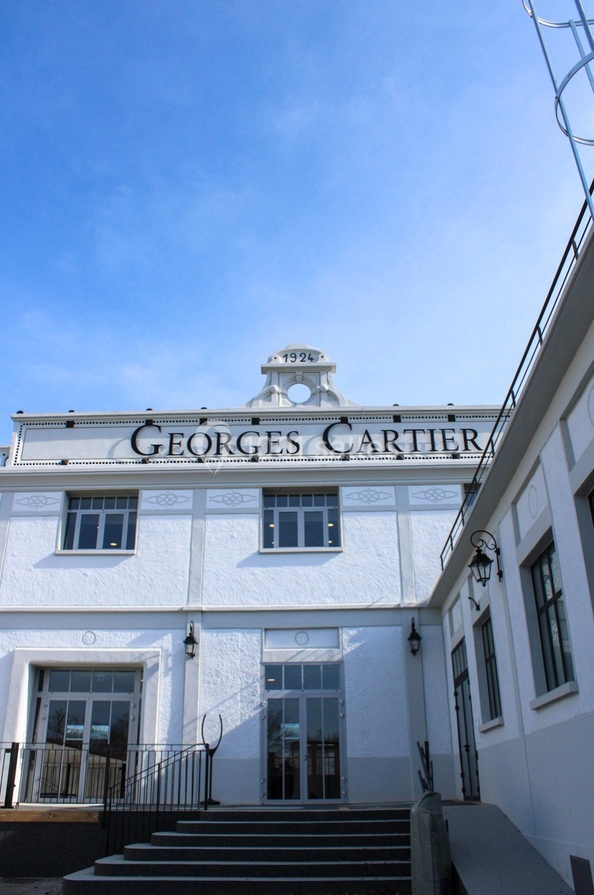 Façade blanche d'un bâtiment avec l'inscription ’Georges Cartier’, sous un ciel bleu dégagé.
