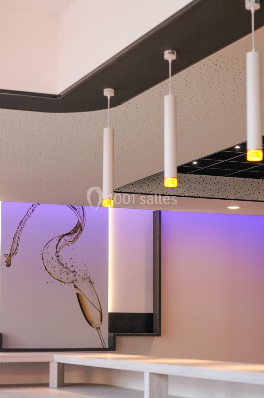Suspensions lumineuses modernes dans un intérieur avec un mur décoré d'une illustration de verre de champagne.