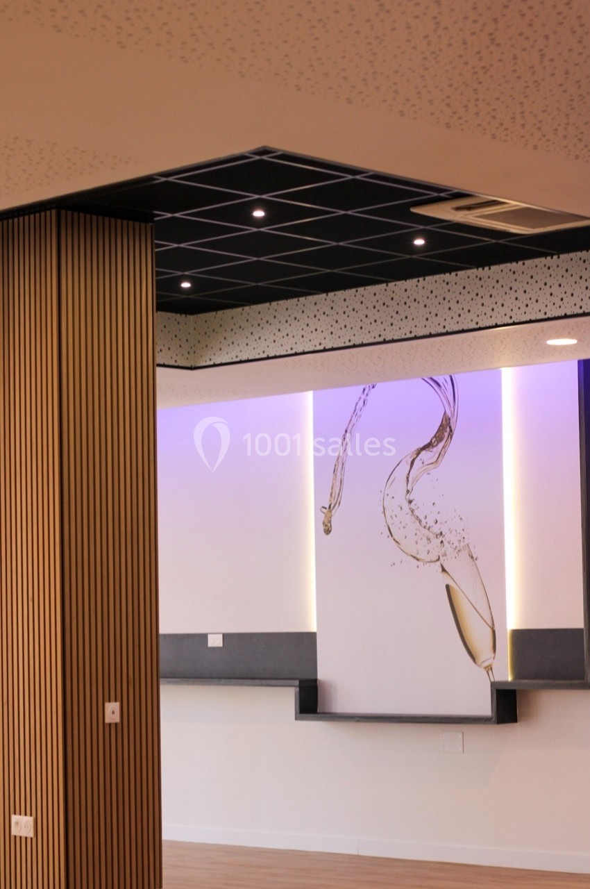 Mur décoratif avec illustration de verre de champagne, éclairage violet et plafond moderne dans un espace intérieur.