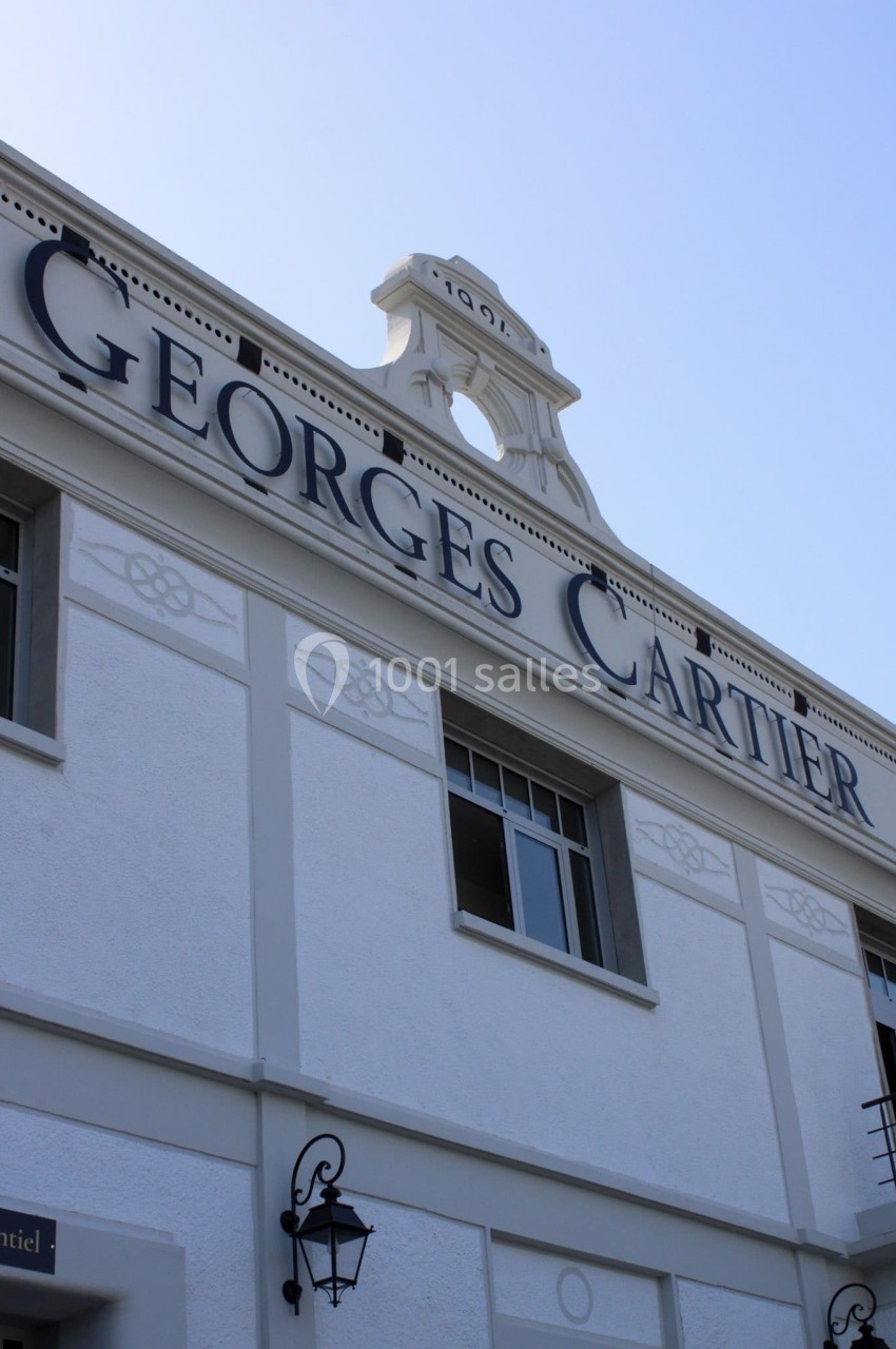Façade d'un bâtiment blanc avec l'inscription ’Georges Cartier’ et des détails architecturaux classiques.