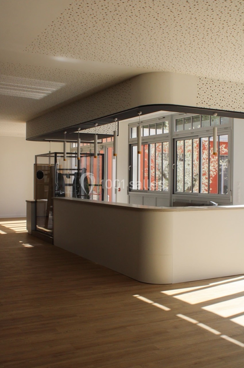 Comptoir moderne dans un espace lumineux avec parquet en bois et grandes fenêtres laissant entrer la lumière naturelle.