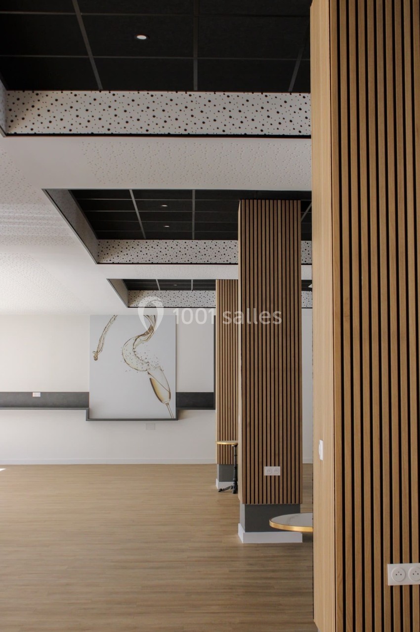Colonnes en bois verticales dans un espace intérieur moderne avec plafond noir et tableau décoratif au mur.