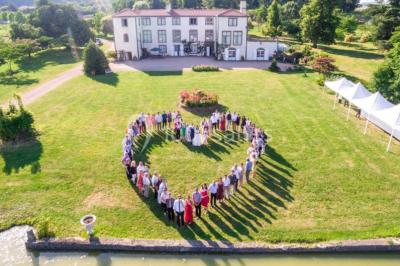 Champ de lotus en fleurs avec des feuilles vertes, des bourgeons et un étang en arrière-plan, entouré d'arbres.