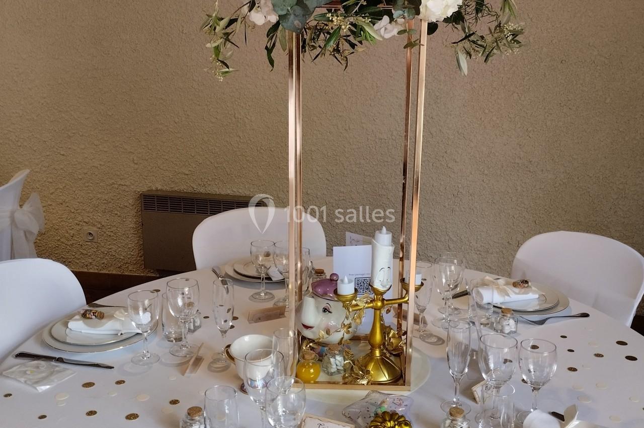 Table de réception décorée avec une composition florale surélevée, vaisselle élégante et accessoires festifs.