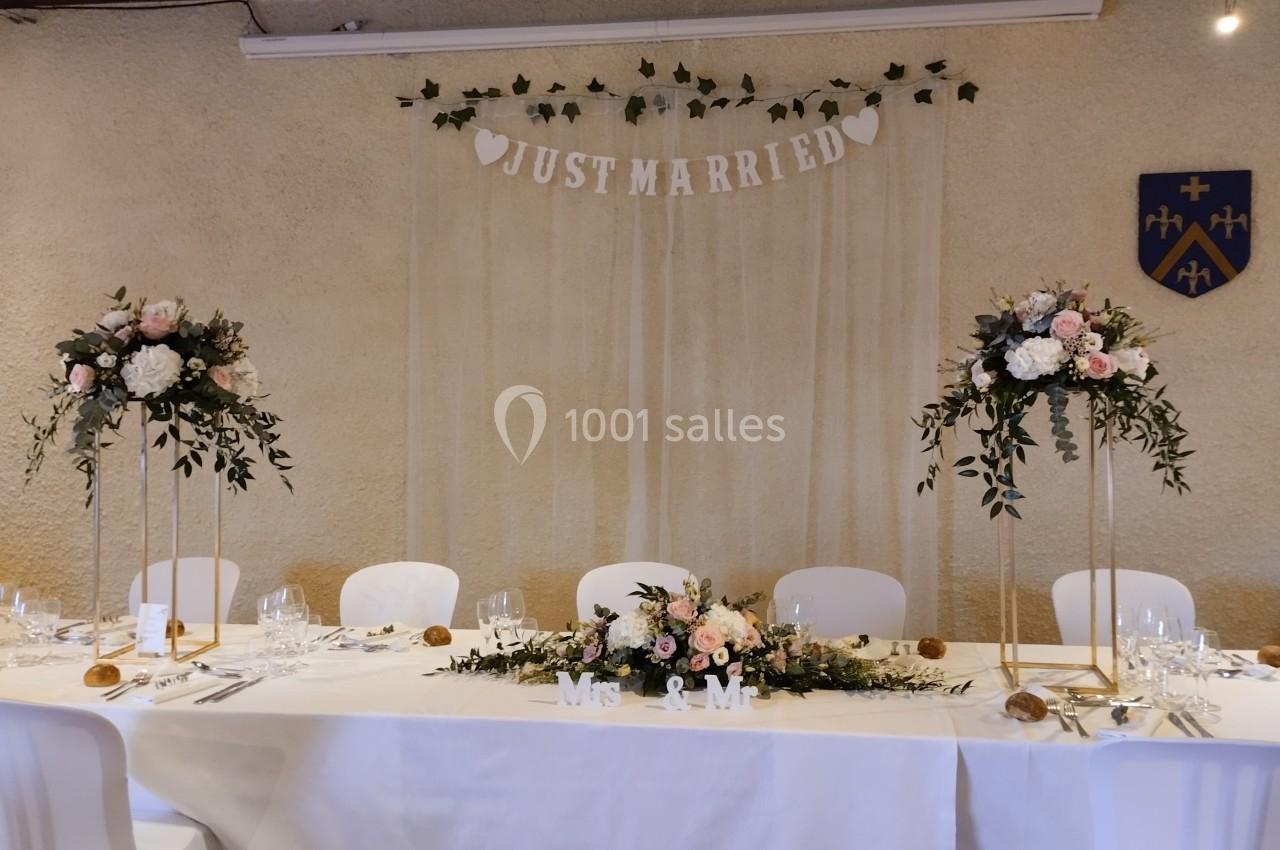 Table de mariage décorée avec des fleurs, des bougies et une bannière ’Just Married’ suspendue en arrière-plan.