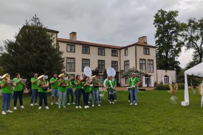 Champ de lotus en fleurs avec des feuilles vertes, des bourgeons et un étang en arrière-plan, entouré d'arbres.