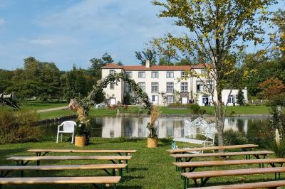 Champ de lotus en fleurs avec des feuilles vertes, des bourgeons et un étang en arrière-plan, entouré d'arbres.