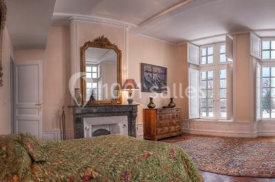 Champ de lotus en fleurs avec des feuilles vertes, des bourgeons et un étang en arrière-plan, entouré d'arbres.