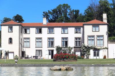 Champ de lotus en fleurs avec des feuilles vertes, des bourgeons et un étang en arrière-plan, entouré d'arbres.