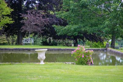 Un groupe de personnes pose devant un tracteur rouge et une machine agricole, devant un grand bâtiment ancien.