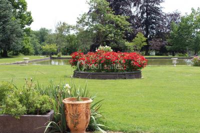 Un groupe de personnes pose devant un tracteur rouge et une machine agricole, devant un grand bâtiment ancien.