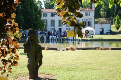 Un groupe de personnes pose devant un tracteur rouge et une machine agricole, devant un grand bâtiment ancien.