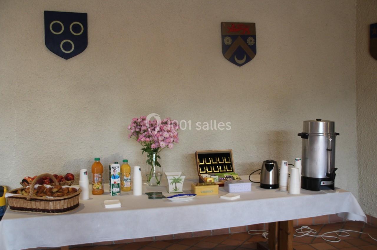 Table avec boissons, viennoiseries, fleurs et machine à café, disposée pour un buffet ou une collation.
