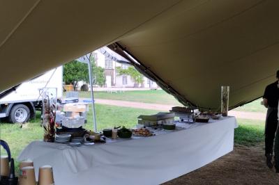 Un groupe de personnes pose devant un tracteur rouge et une machine agricole, devant un grand bâtiment ancien.