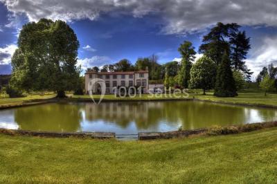 Un groupe de personnes pose devant un tracteur rouge et une machine agricole, devant un grand bâtiment ancien.