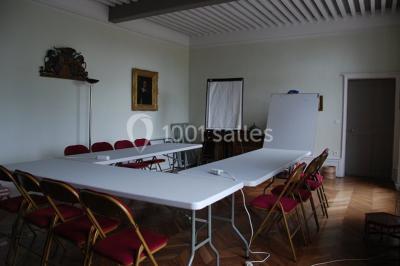 Un groupe de personnes pose devant un tracteur rouge et une machine agricole, devant un grand bâtiment ancien.