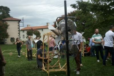 Un groupe de personnes pose devant un tracteur rouge et une machine agricole, devant un grand bâtiment ancien.