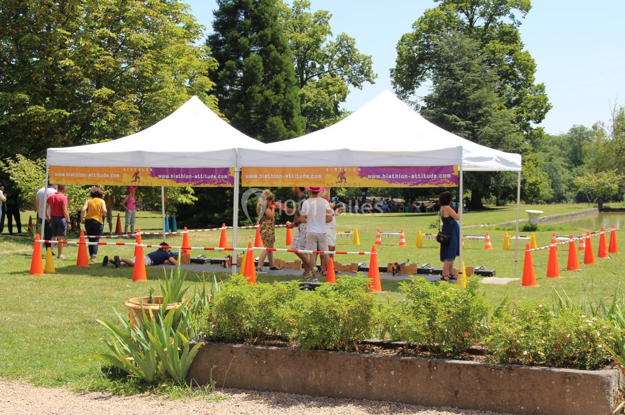 Des personnes participent à une activité en plein air sous des tentes blanches, entourées de cônes de signalisation orange.