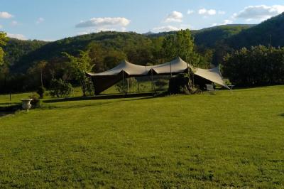 Un groupe de personnes pose devant un tracteur rouge et une machine agricole, devant un grand bâtiment ancien.