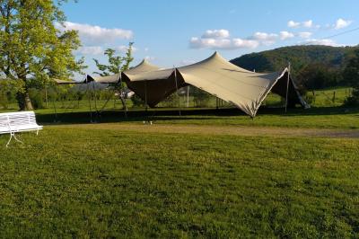 Un groupe de personnes pose devant un tracteur rouge et une machine agricole, devant un grand bâtiment ancien.