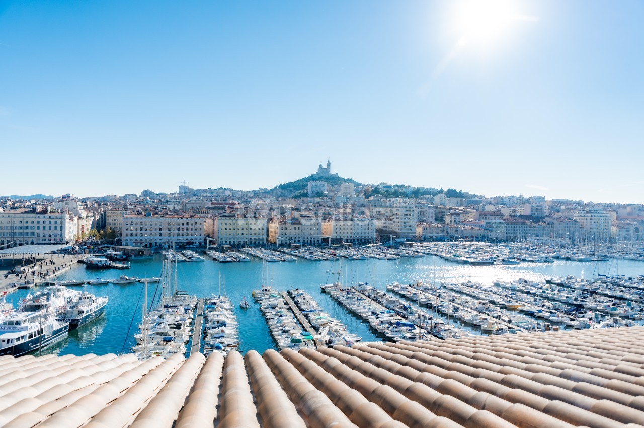 Vue sur le Vieux-Port de Marseille avec ses nombreux bateaux amarrés, la ville et la basilique Notre-Dame de la Garde en…
