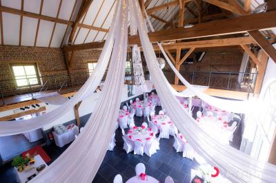 Table de réception décorée avec nappes blanches, serviettes vertes pliées, chaises ornées de nœuds verts et centre de table…