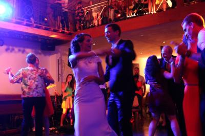 Table de réception décorée avec nappes blanches, serviettes vertes pliées, chaises ornées de nœuds verts et centre de table…