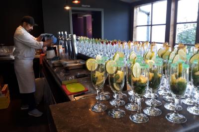 Table de réception décorée avec nappes blanches, serviettes vertes pliées, chaises ornées de nœuds verts et centre de table…